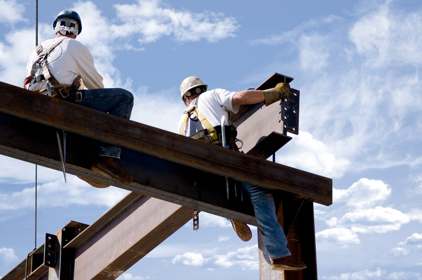 Two ironworkers atop the skeleton of a modern building